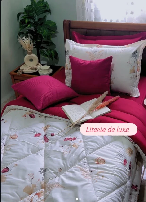 Lit avec parure fleurie blanche, draps et coussins fuchsia